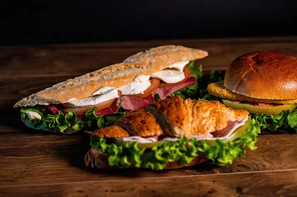 夹有腊肠和蔬菜在木制表面的三明治组合 — 图库照片