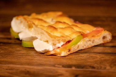 Tahta bir yüzeyde sebzeler ve sebzelerle doldurulmuş Focaccia.