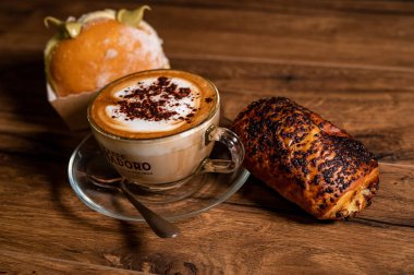 Terni, İtalya 26 Ekim 2021: ahşap bir yüzeyde kremalı ve kapuçinolu tatlı kruvasanlar.