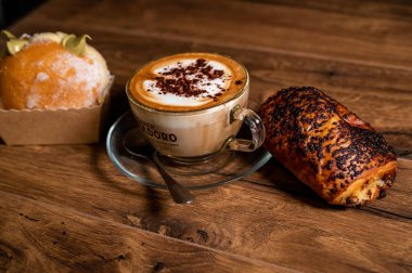 Terni, İtalya 26 Ekim 2021: ahşap bir yüzeyde kremalı ve kapuçinolu tatlı kruvasanlar.