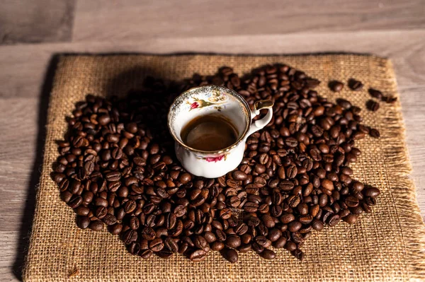 Xícara de café em meio a grãos de café — Fotografia de Stock
