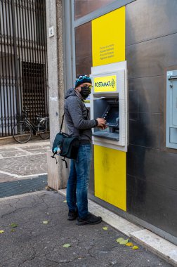 Terni, İtalya 23 Aralık 2021: Postanedeki para çekme makinesindeki adam.
