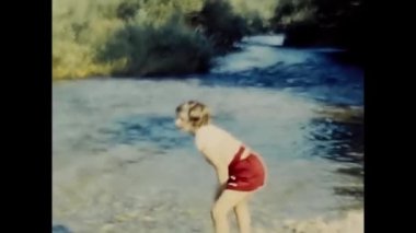 Palermo, İtalya Mart 1950 'de nehir kıyısında lastik çizmeli şirin bir kız oynuyor.