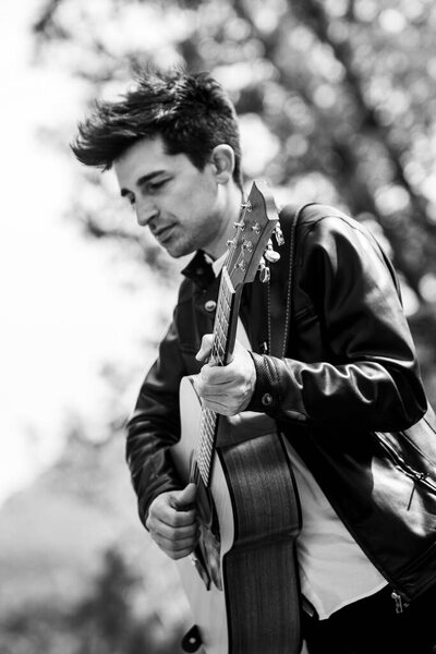 boy plays black and white guitar in nature