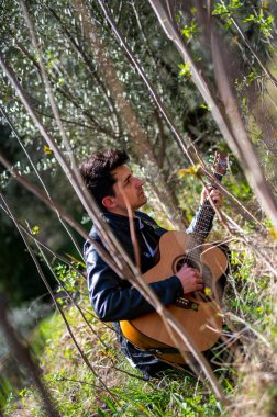 Terni, İtalya 15 Nisan 2022: Çocuk doğayla iç içe gitar çalıyor