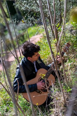 Terni, İtalya 15 Nisan 2022: Çocuk doğayla iç içe gitar çalıyor