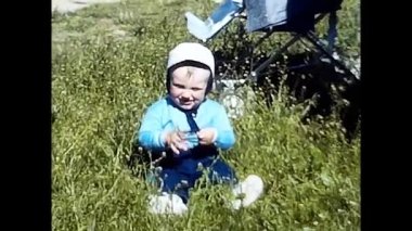 Milan, İtalya 18 Mart 1980. Çocuk 80 'lerde çimlerin üzerinde oturuyor.