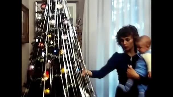 1980年8月18日 意大利米兰 妈妈在一棵80多岁的圣诞树旁抱着孩子 — 图库视频影像