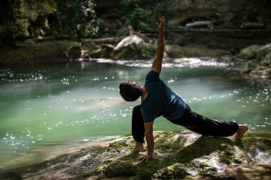 Gündüz vakti nehirde yoga yapan bir çocuk.