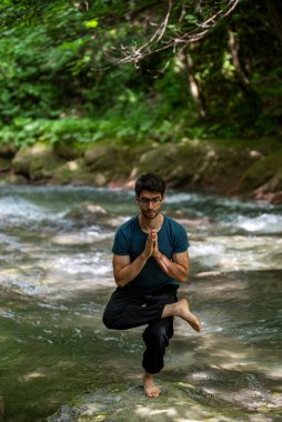 Gündüz vakti nehirde yoga yapan bir çocuk.
