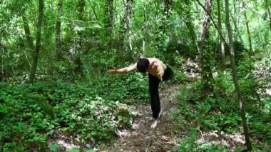 Çocuk ormanda yoga yapıyor. Tamamen rahatlamış.