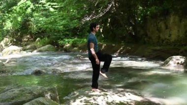 Çocuk nehir kıyısında yoga yapıyor. Tamamen rahatlamış.