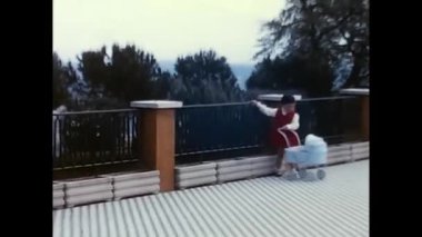 Roma, İtalya 18 Nisan 1970. Küçük kız 70 'lerin oyuncak bebek arabasıyla oynuyor.