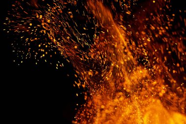 Siyah arkaplanda kıvılcımlar saçan bir ateş alevi
