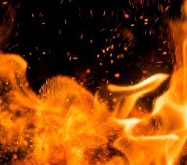 Siyah arkaplanda kıvılcımlar saçan bir ateş alevi