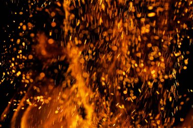 Siyah arkaplanda kıvılcımlar saçan bir ateş alevi