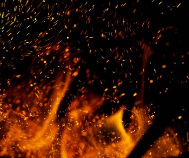 Siyah arkaplanda kıvılcımlar saçan bir ateş alevi
