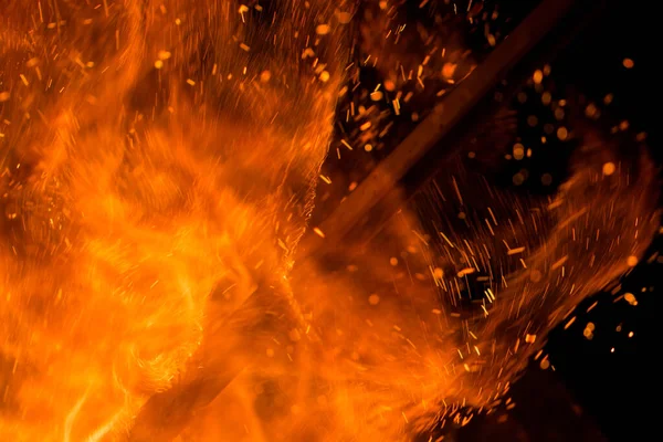 Siyah arkaplanda kıvılcımlar saçan bir ateş alevi