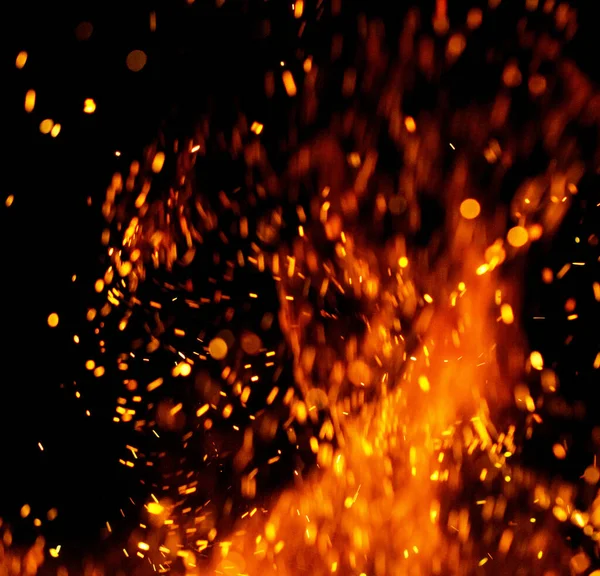 Siyah arkaplanda kıvılcımlar saçan bir ateş alevi