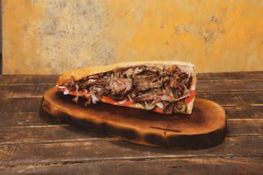 Doner kebabı kesme tahtasının üzerinde duruyor. Et, soğan ve salata ile Shawarma eski ve karanlık bir tahta masada yatıyor.