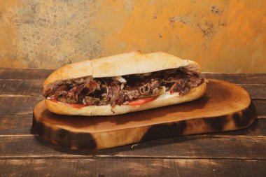 Doner kebabı kesme tahtasının üzerinde duruyor. Et, soğan ve salata ile Shawarma eski ve karanlık bir tahta masada yatıyor.