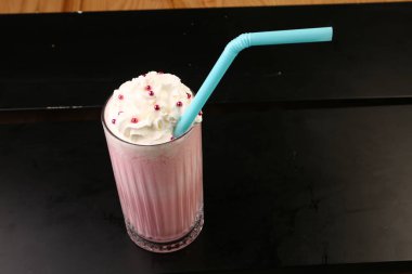 Bir bardak ahududu milkshake, krem şanti ve taze ahududu.