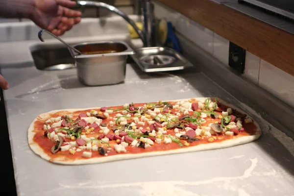 stock image Pizza chef put sauce on base in a commercial kitchen