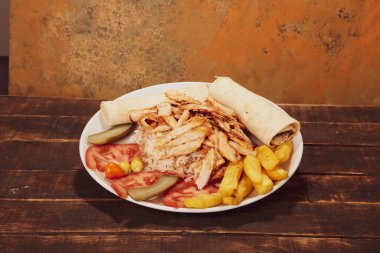 Doner kebabı kesme tahtasının üzerinde duruyor. Et, soğan ve salata ile Shawarma eski ve karanlık bir tahta masada yatıyor.