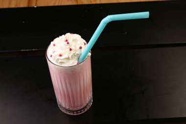 Bir bardak ahududu milkshake, krem şanti ve taze ahududu.