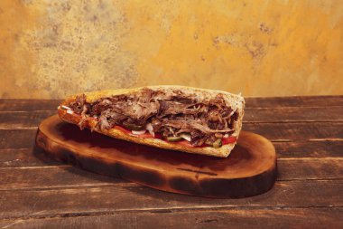 Doner kebabı kesme tahtasının üzerinde duruyor. Et, soğan ve salata ile Shawarma eski ve karanlık bir tahta masada yatıyor.