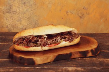 Doner kebabı kesme tahtasının üzerinde duruyor. Et, soğan ve salata ile Shawarma eski ve karanlık bir tahta masada yatıyor.