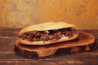 Doner kebabı kesme tahtasının üzerinde duruyor. Et, soğan ve salata ile Shawarma eski ve karanlık bir tahta masada yatıyor.