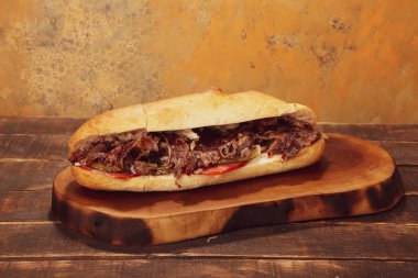 Doner kebabı kesme tahtasının üzerinde duruyor. Et, soğan ve salata ile Shawarma eski ve karanlık bir tahta masada yatıyor.