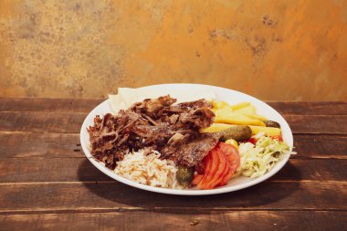 Doner kebabı kesme tahtasının üzerinde duruyor. Et, soğan ve salata ile Shawarma eski ve karanlık bir tahta masada yatıyor.