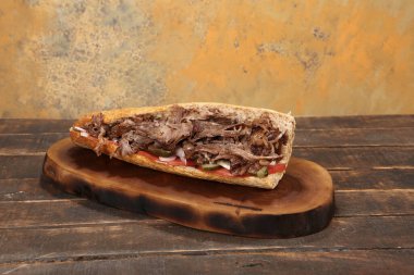 Doner kebabı kesme tahtasının üzerinde duruyor. Et, soğan ve salata ile Shawarma eski ve karanlık bir tahta masada yatıyor.