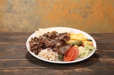 Doner kebabı kesme tahtasının üzerinde duruyor. Et, soğan ve salata ile Shawarma eski ve karanlık bir tahta masada yatıyor.