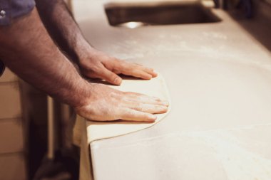 Pizza şefi ticari bir mutfakta sosu tabana koydu.