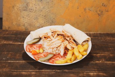 Doner kebabı kesme tahtasının üzerinde duruyor. Et, soğan ve salata ile Shawarma eski ve karanlık bir tahta masada yatıyor.