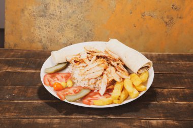 Doner kebabı kesme tahtasının üzerinde duruyor. Et, soğan ve salata ile Shawarma eski ve karanlık bir tahta masada yatıyor.