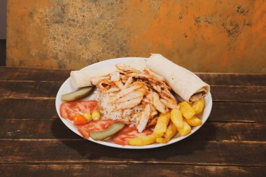 Doner kebabı kesme tahtasının üzerinde duruyor. Et, soğan ve salata ile Shawarma eski ve karanlık bir tahta masada yatıyor.