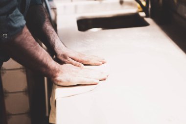 Pizza şefi ticari bir mutfakta sosu tabana koydu.