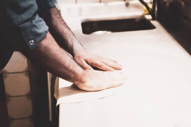 Pizza şefi ticari bir mutfakta sosu tabana koydu.