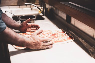 Pizza şefi ticari bir mutfakta sosu tabana koydu.