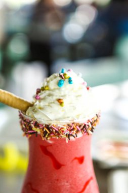 Bir bardak ahududu milkshake, krem şanti ve taze ahududu.