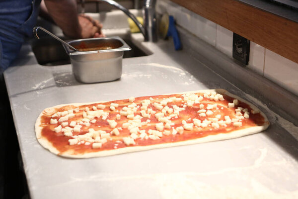 Pizza chef put sauce on base in a commercial kitchen