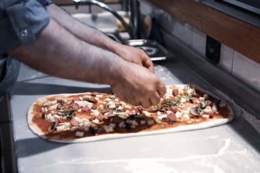 Pizza şefi ticari bir mutfakta sosu tabana koydu.