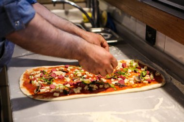 Pizza şefi ticari bir mutfakta sosu tabana koydu.