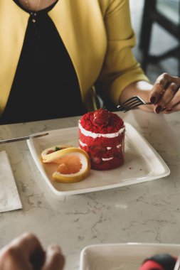 Bir kafede pasta yiyen bir kadının yakın çekimi.