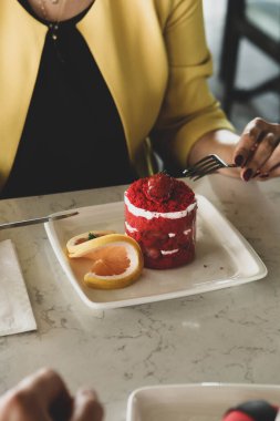 Bir kafede pasta yiyen bir kadının yakın çekimi.