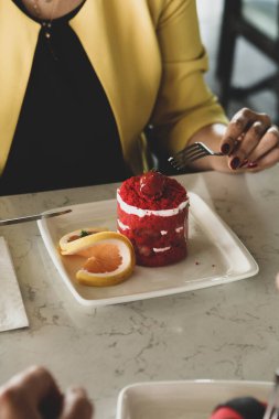 Bir kafede pasta yiyen bir kadının yakın çekimi.